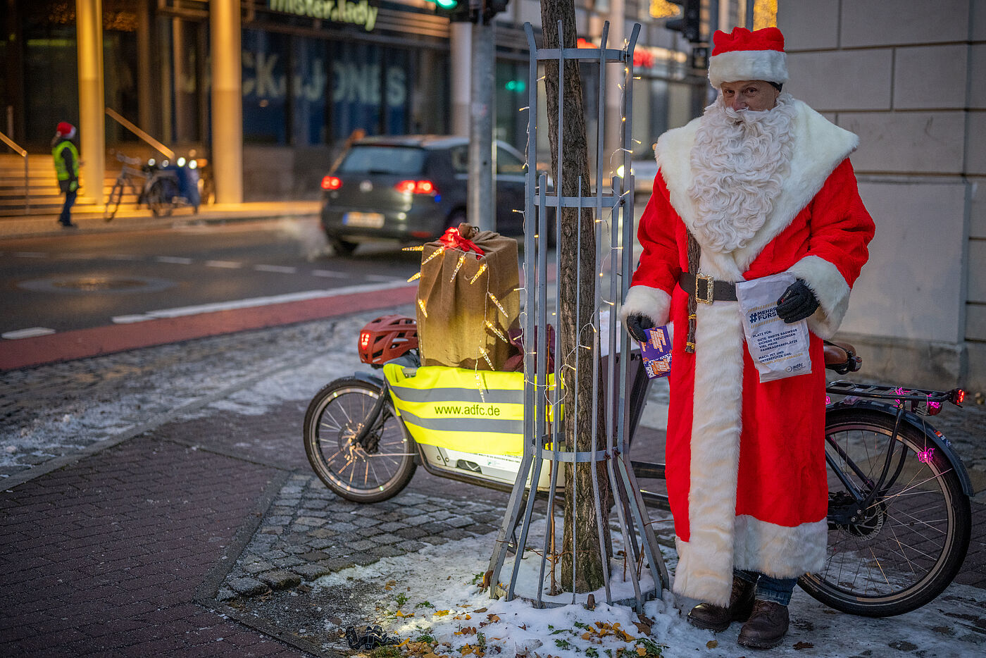 gestelltes Bild mit Nikolaus mit Geschenken und Lastenfahrrad und im Hintergrund eine Helferin