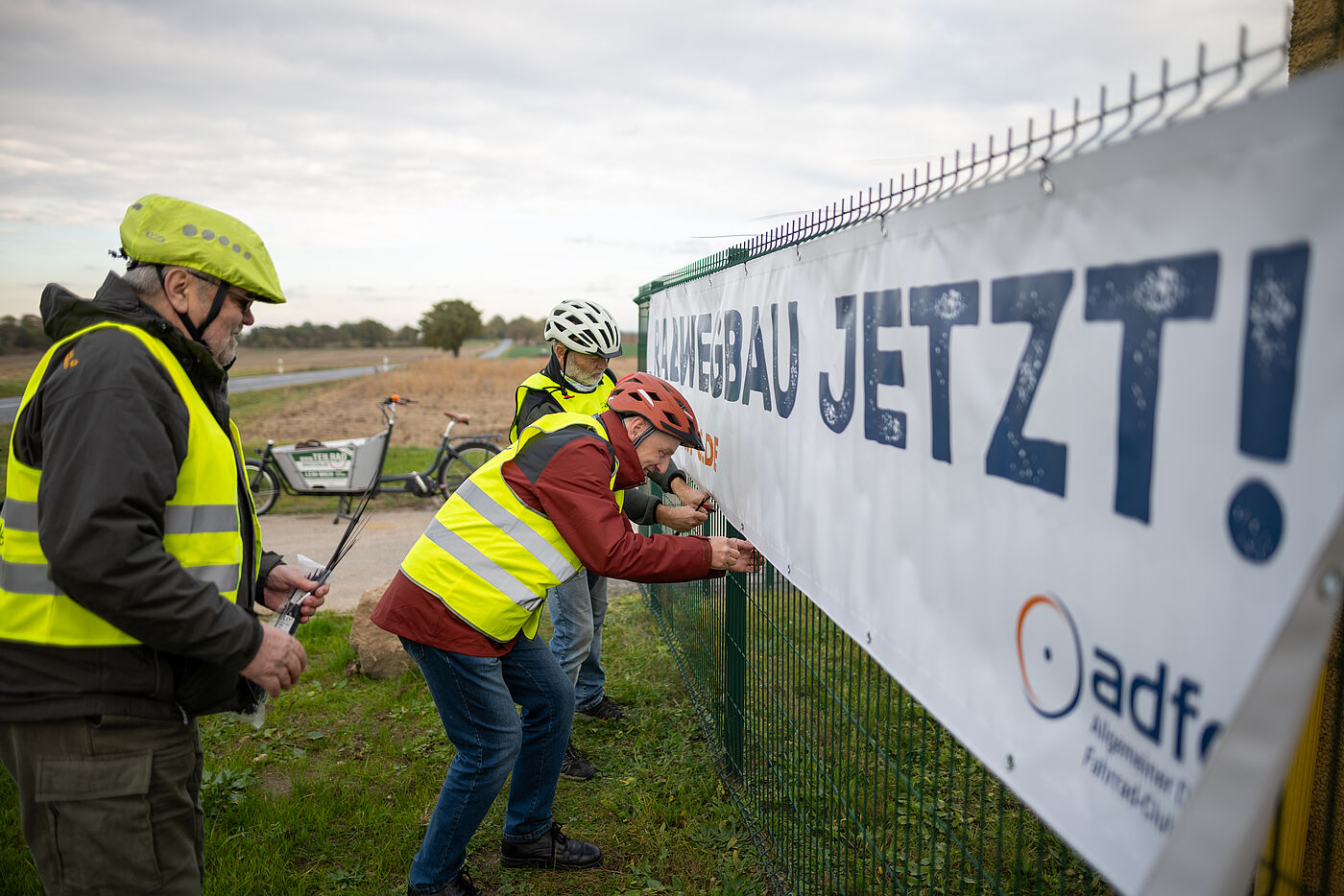 Der Banner wird durch Mitglieder an der Staatsstraße angebracht.