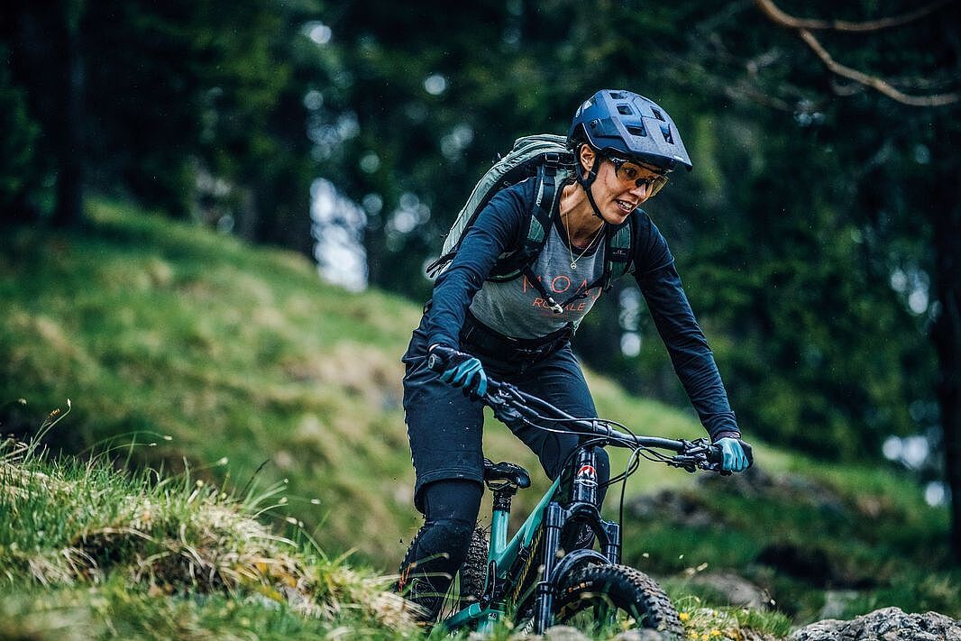 Frau auf einem Mountainbike im Wald mit Helm